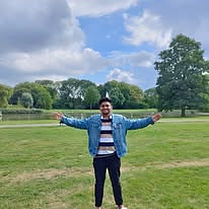 Saiful Islam standing with open arms in a green park